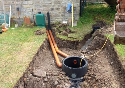 A sewage treatment plant in the ground with pipe connections mid way through installation