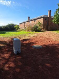 A newly installed sewage treatment plant in the garden showing the property in the background