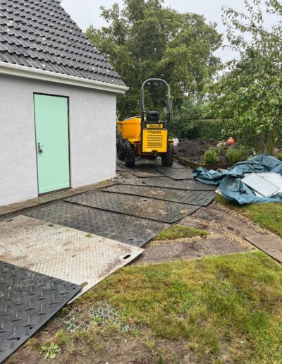 Use of protective matting laid over a garden lawn to protect from heavy machinery