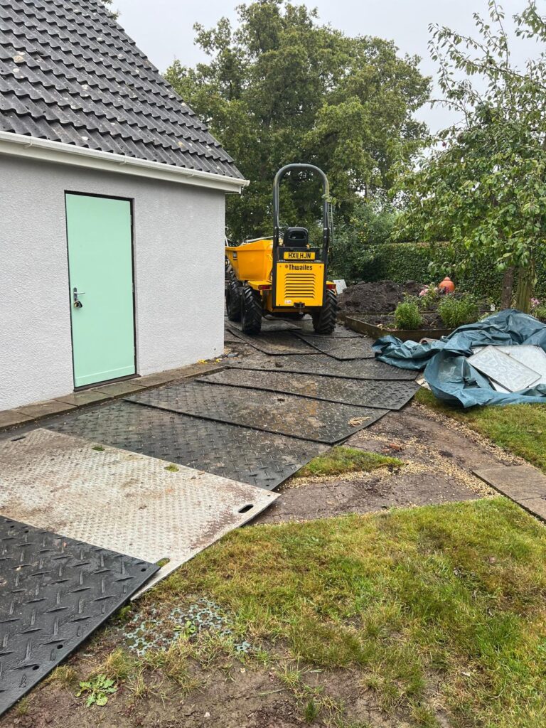 Use of protective matting laid over a garden lawn to protect from heavy machinery