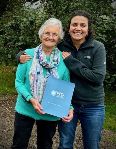 Naomi Taylor presenting a cheque inside a WCI folder to a customer