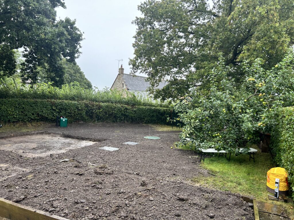 Photo of a newly installed sewage treatment plant in a garden and a kiosk along the hedge line