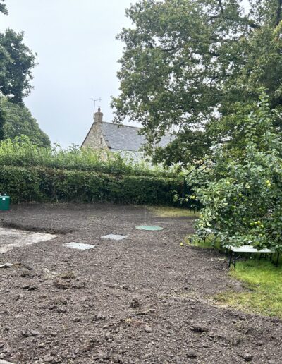Photo of a newly installed sewage treatment plant in a garden and a kiosk along the hedge line