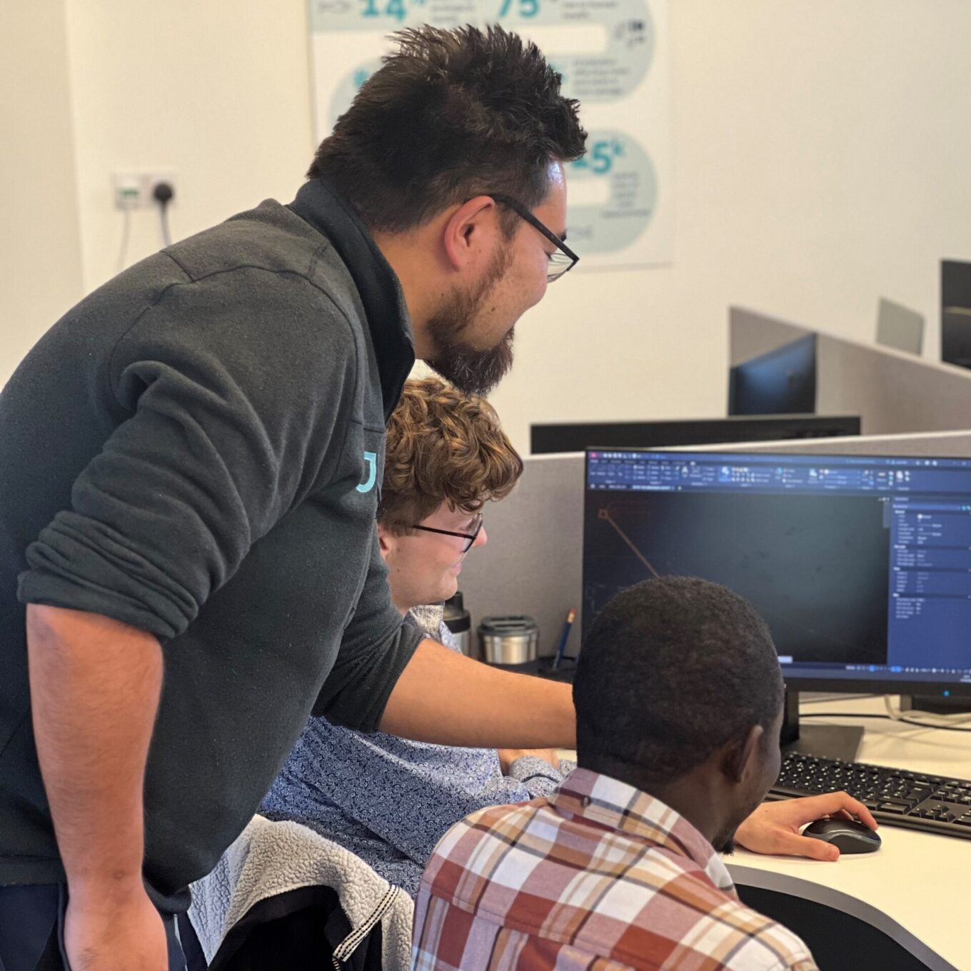 Picture of three engineers gathered around a computer screen discussing an engineering project