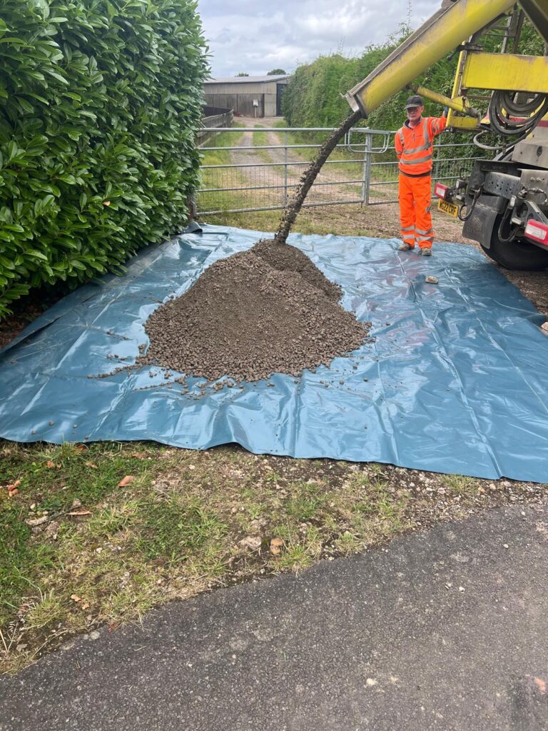 Concrete being emptied from a lorry onto a tarpaulin in a gateway